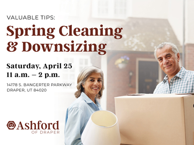 A smiling older man and woman hold moving boxes and a lamp. Text advertises a spring cleaning and downsizing event on April 25, 11 a.m.–2 p.m., at Ashford of Draper, 14178 S. Bangerter Parkway, Draper, UT.